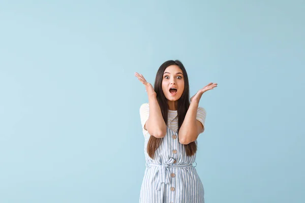 Portrait of surprised young woman on color background