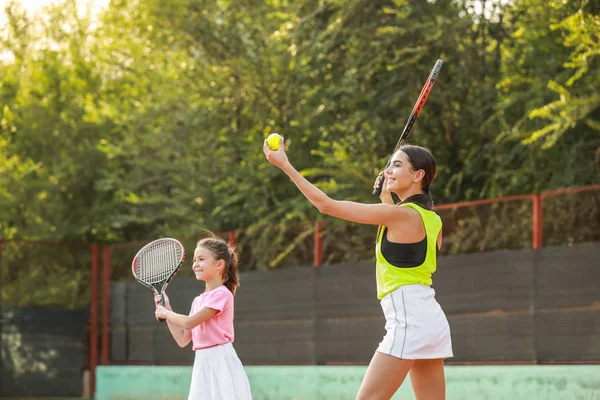 Klein meisje en haar moeder tennissen op het veld — Stockfoto