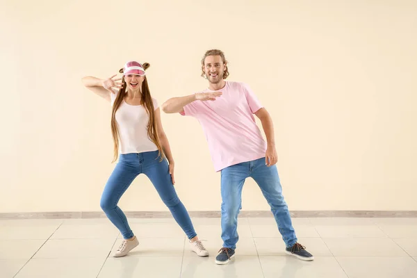 Cool young couple dancing against light wall — Stock Photo, Image