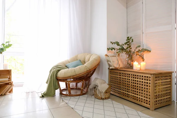 Zachte stoel met eucalyptus takken en brandende kaarsen in het interieur van de kamer — Stockfoto