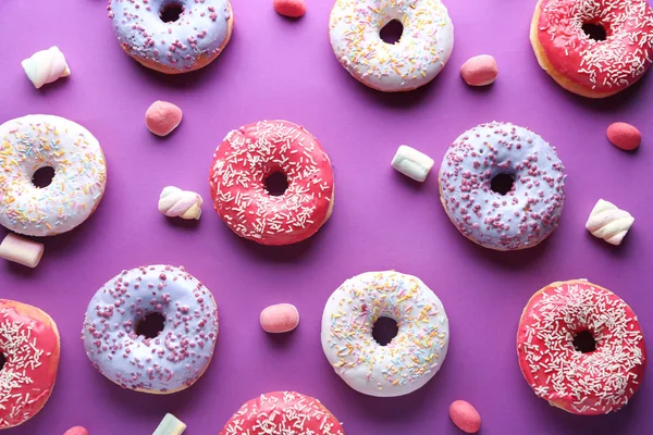Verschiedene leckere Donuts mit Bonbons auf farbigem Hintergrund — Stockfoto