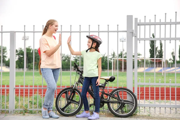 Η μητέρα και η μικρή της κόρη με το ποδήλατο που δίνει ο ένας στον άλλο σε εξωτερικούς χώρους — Φωτογραφία Αρχείου