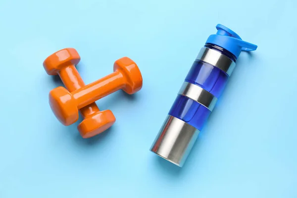 Sports water bottle and dumbbells on color background — Stock Photo, Image