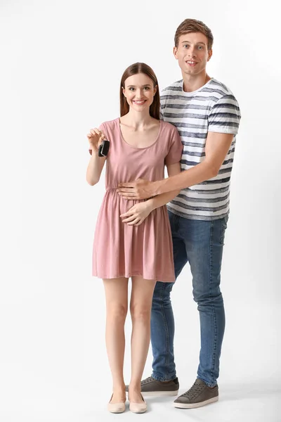 Feliz joven pareja con llave de coche nuevo sobre fondo blanco — Foto de Stock