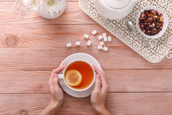 Young woman drinking hot tea at wooden table — Stock Photo, Image