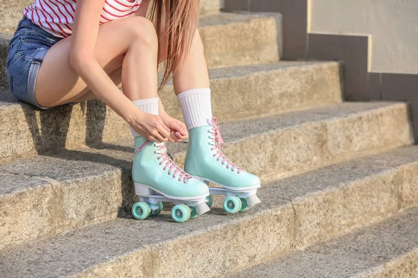 Mooie jonge vrouw putting roller skates buitenshuis — Stockfoto