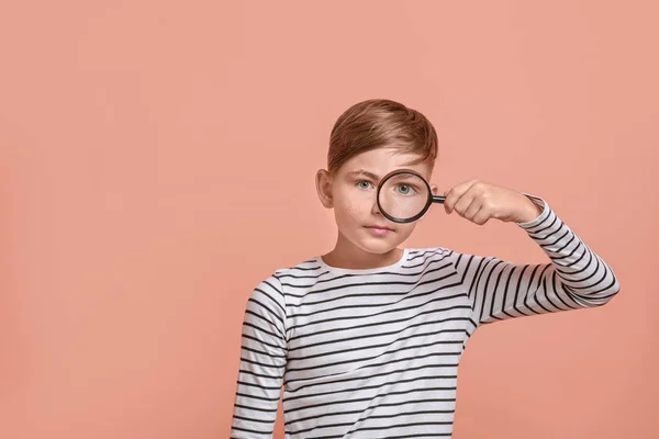 Little boy with magnifying glass on color background — Stock Photo, Image