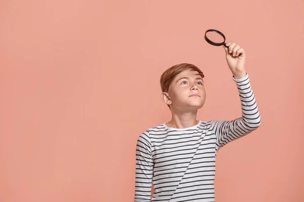 Little boy with magnifying glass on color background — Stock Photo, Image