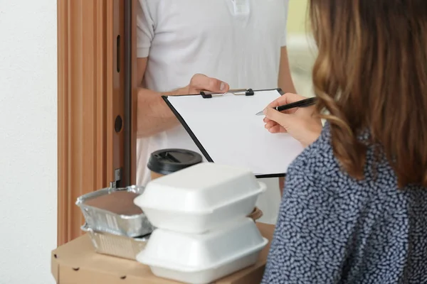 Woman signing documents to confirm receiving of order from food delivery company — Stock Photo, Image