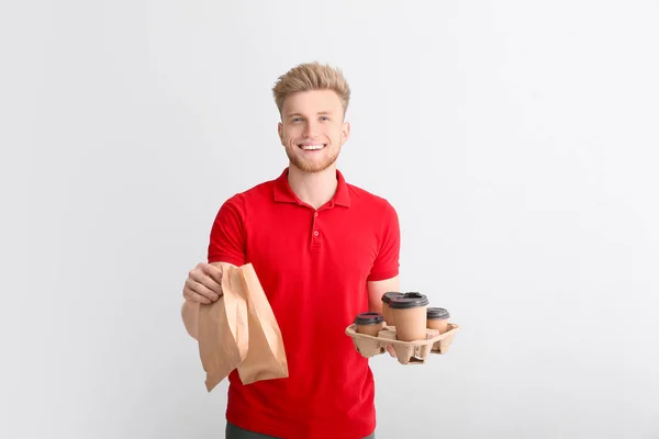 Handsome worker of food delivery service on light background — Stock Photo, Image