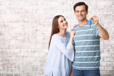 Tuğla arka plan üzerinde yeni araba dan anahtar ile Mutlu çift