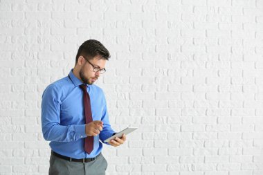 Beyaz tuğla duvara karşı tablet bilgisayar ile işadamı portresi