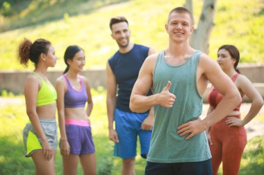 Genç sportif adam açık havada başparmak-up jest gösteren