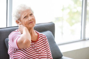 Evde boyun ağrısı çeken yaşlı kadın