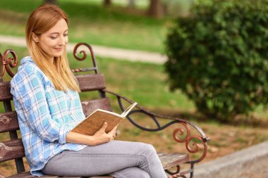 Parkta dinlenirken kitap okuyan kadın