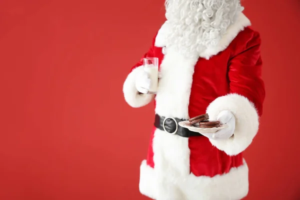 Santa Claus s mlékem a sušenkama na barevném pozadí — Stock fotografie