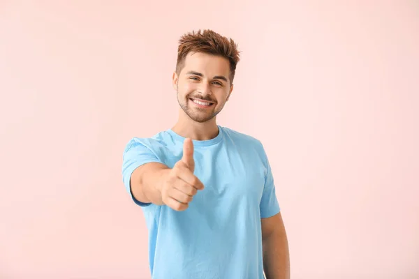 Portrait of happy young man showing thumb-up gesture on color background — Stock Photo, Image