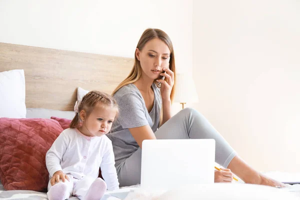 Arbetande mamma med sin dotter i sovrummet hemma — Stockfoto