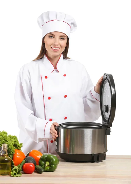 Женский шеф-повар с современной мульти-плитой и продуктами за столом на белом фоне — стоковое фото