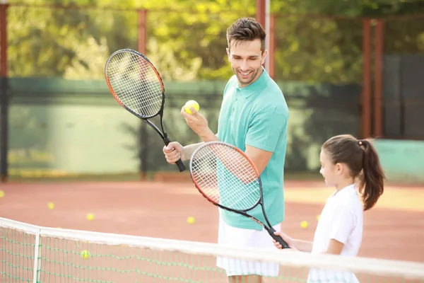 Klein meisje en haar vader spelen tennis op de baan — Stockfoto