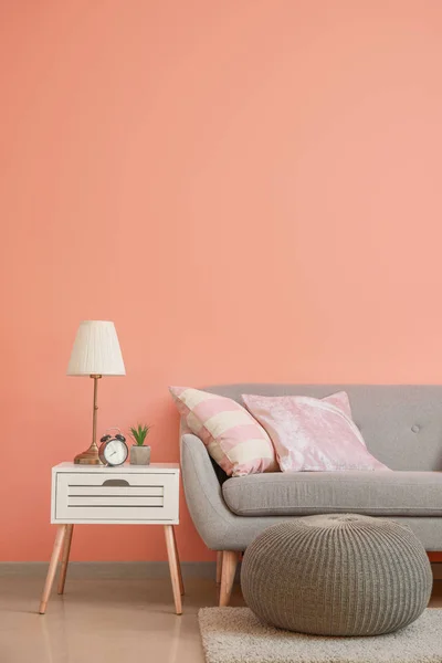 Cozy sofa with pouf and table near color wall in room — Stock Photo, Image