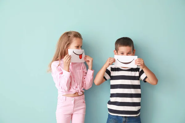 Little children hiding mouths behind drawn smiles on color background — Stock Photo, Image