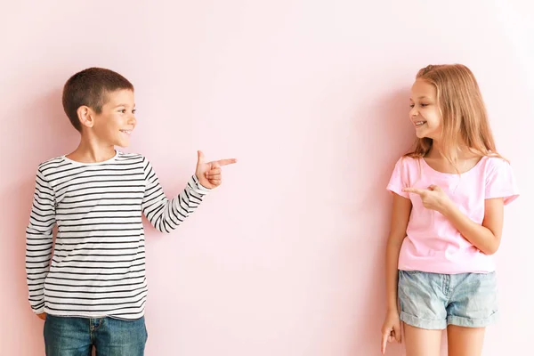 Портрет счастливых маленьких детей, указывающих друг на друга на цветном фоне — стоковое фото