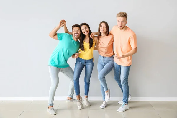Group of young people in stylish casual clothes near light wall — Stock Photo, Image