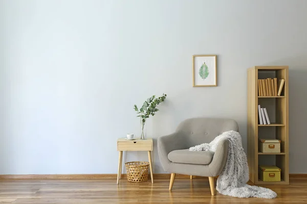 Stílusos belső helyiség fotel és eukaliptusz ágak vázában az asztalon — Stock Fotó