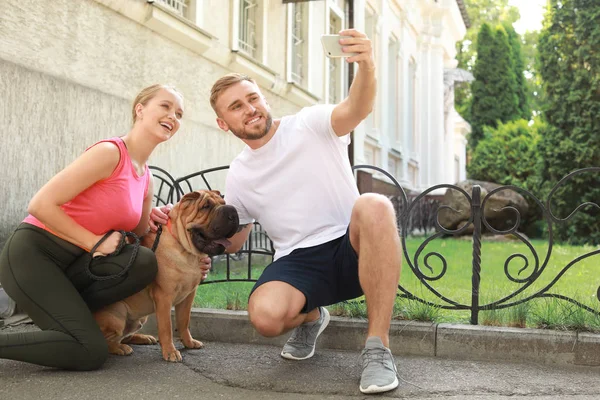 Αθλητικό ζευγάρι με χαριτωμένο σκυλί λήψη selfie σε εξωτερικούς χώρους — Φωτογραφία Αρχείου