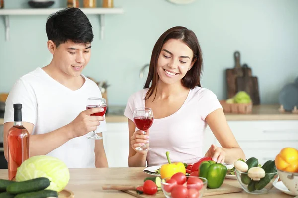 Casal feliz bebendo vinho enquanto cozinha na cozinha — Fotografia de Stock