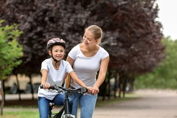 Mother teaching her daughter to ride bicycle outdoors — Stock Photo, Image