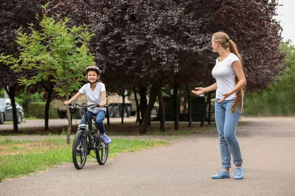 Mãe ensinando sua filha a andar de bicicleta ao ar livre — Fotografia de Stock