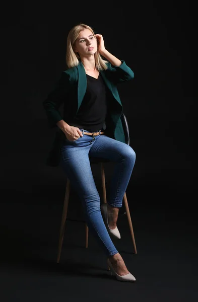 Bonita mulher de negócios elegante sentada na cadeira contra fundo escuro — Fotografia de Stock