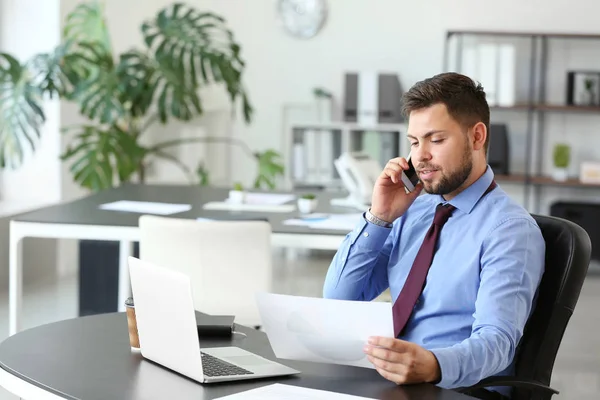 Portrait of businessman talking by phone in office — Stock Photo, Image