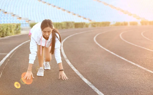 Sporty Asian woman in crouch start position at the stadium — Stock Photo, Image