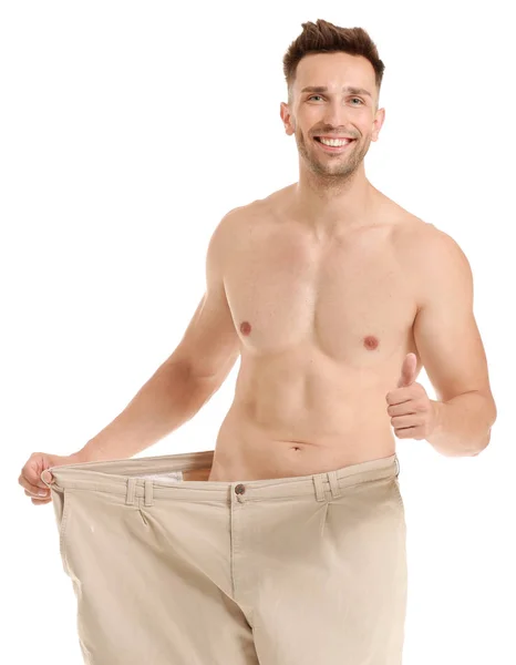 Knappe gespierde man in losse broek op witte achtergrond. Gewichtsverlies concept — Stockfoto