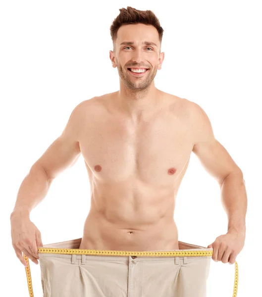 Handsome muscular man in loose pants on white background. Weight loss concept — Stock Photo, Image