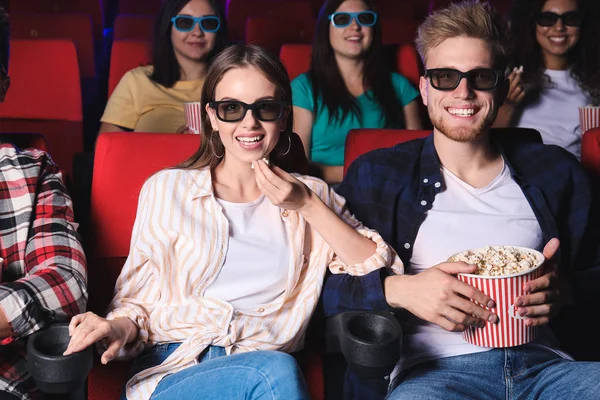 Friends with popcorn watching movie in cinema — Stock Photo, Image