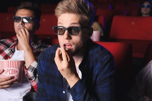 Young man with popcorn watching movie in cinema — Stock Photo, Image