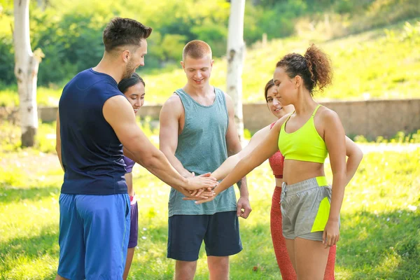 Group of young sporty people putting hands together outdoors — Stock Photo, Image