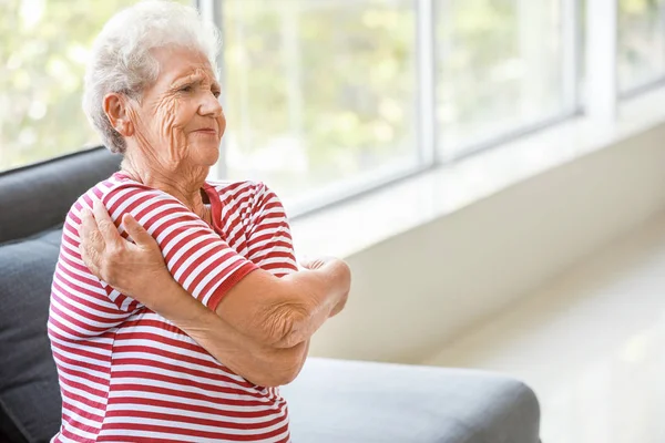 Senior woman suffering from pain in shoulder at home — Stock Photo, Image