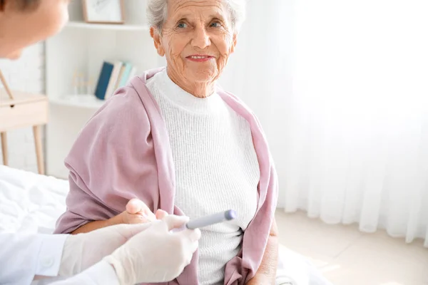 Doctor taking blood sample of diabetic woman at home — Stock Photo, Image