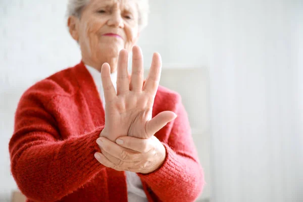 Senior woman suffering from pain in wrist at home, closeup — Stock Photo, Image