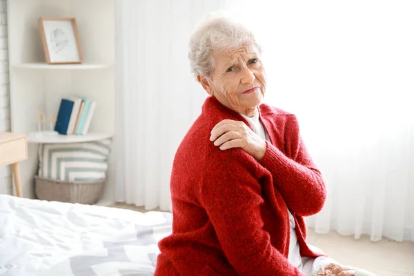 Senior woman suffering from pain in shoulder at home — Stock Photo, Image