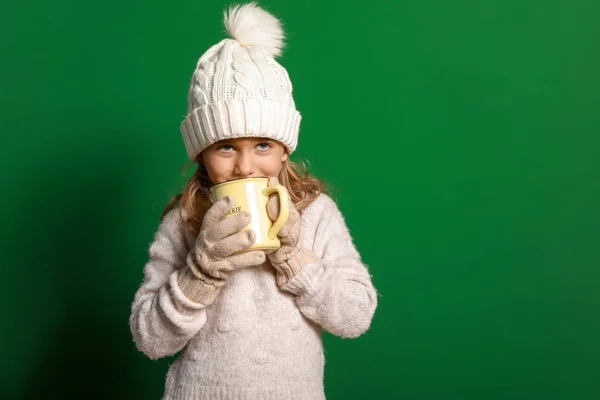 Мила маленька дівчинка з чашкою гарячого шоколаду на кольоровому фоні — стокове фото