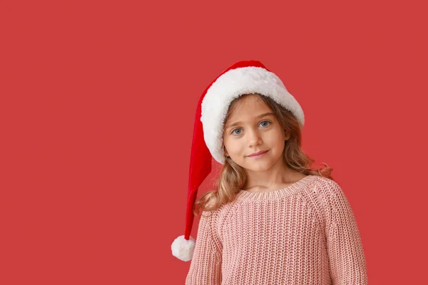 Menina bonito em chapéu de Papai Noel na cor de fundo — Fotografia de Stock