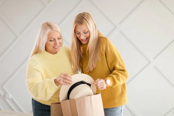 Porträtt av lycklig mor och dotter med ny hatt på grå bakgrund — Stockfoto