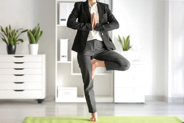Young businesswoman practicing yoga in office