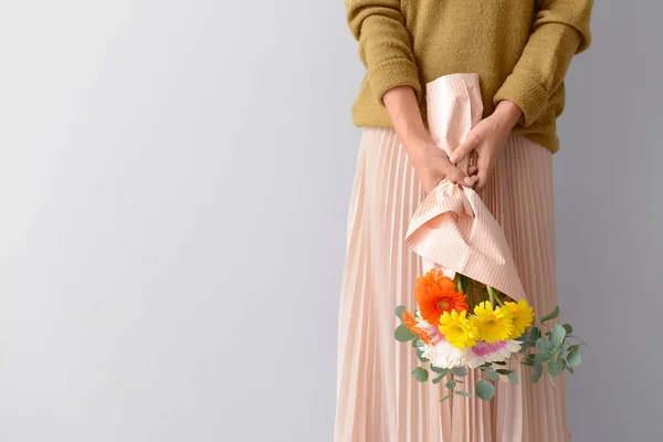 Mujer con ramo de hermosas flores de gerberas sobre fondo claro —  Fotos de Stock